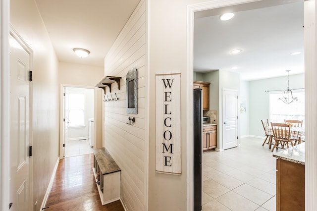 hall with a wealth of natural light, a notable chandelier, and light hardwood / wood-style floors