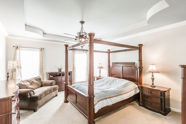 carpeted bedroom with crown molding, a tray ceiling, and ceiling fan