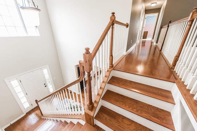 staircase featuring hardwood / wood-style floors, a high ceiling, and plenty of natural light