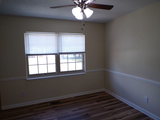 empty room featuring ceiling fan and dark hardwood / wood-style flooring