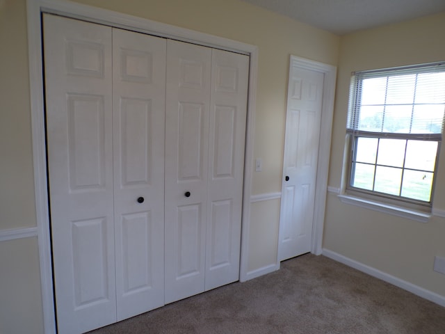 unfurnished bedroom with a closet and light colored carpet