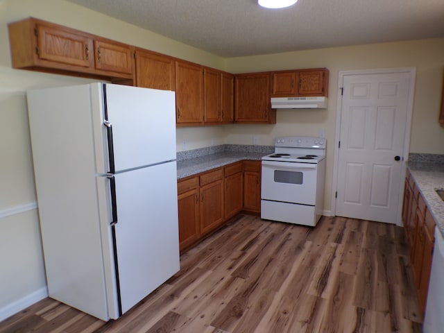 kitchen with hardwood / wood-style floors, a textured ceiling, and white appliances