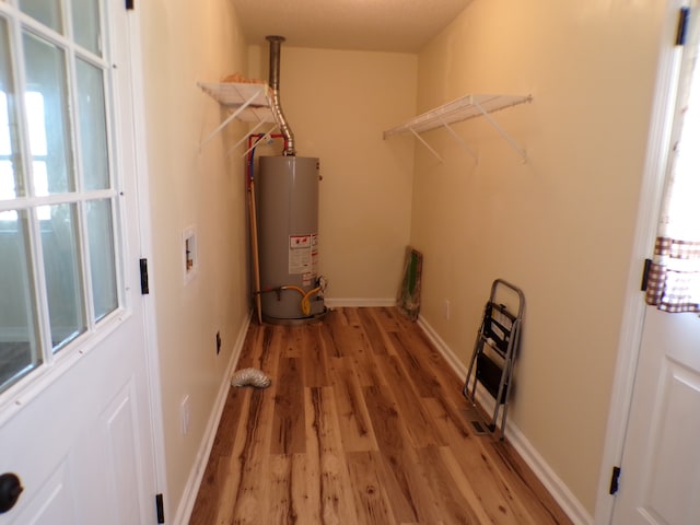 laundry area with hardwood / wood-style floors, gas water heater, and plenty of natural light