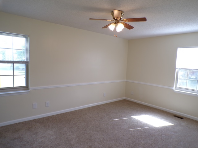 carpeted spare room with a textured ceiling and ceiling fan