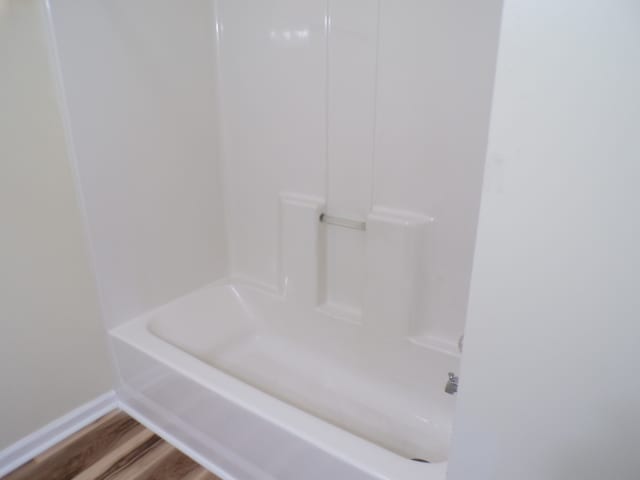 bathroom featuring hardwood / wood-style floors and washtub / shower combination