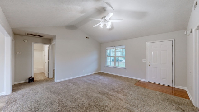 carpeted spare room with a textured ceiling, ceiling fan, and vaulted ceiling