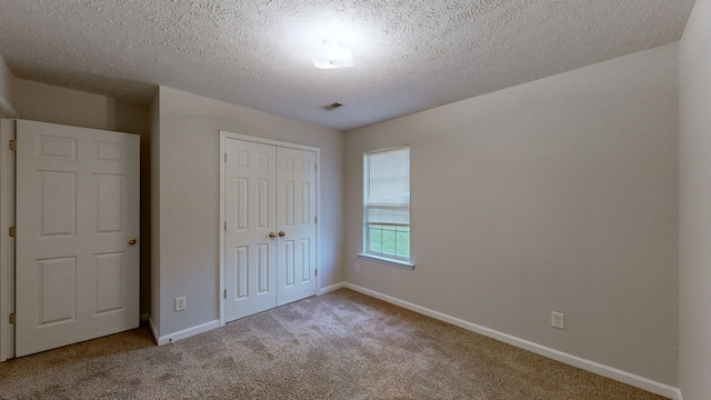 unfurnished bedroom featuring a textured ceiling, carpet floors, and a closet