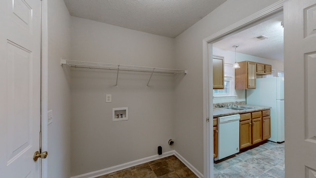 clothes washing area featuring hookup for a washing machine, a textured ceiling, and sink