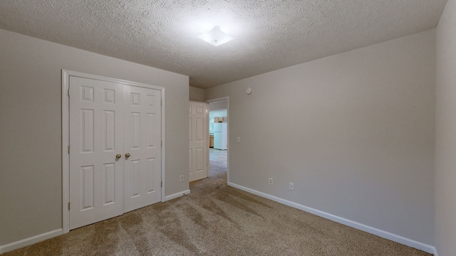 unfurnished bedroom with a textured ceiling, white refrigerator, light carpet, and a closet