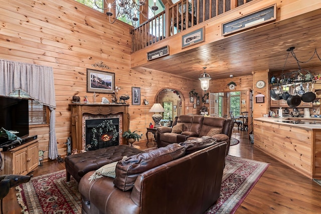 living room with wood walls, a premium fireplace, dark hardwood / wood-style flooring, and a high ceiling