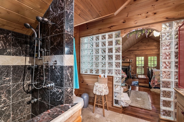 bathroom featuring wood ceiling, wooden walls, vaulted ceiling, vanity, and a tile shower