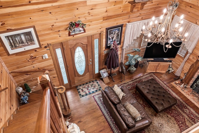 foyer entrance featuring a notable chandelier, wood walls, a towering ceiling, and hardwood / wood-style floors