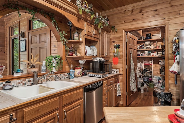 kitchen with dishwasher, tile counters, wooden walls, sink, and dark hardwood / wood-style flooring