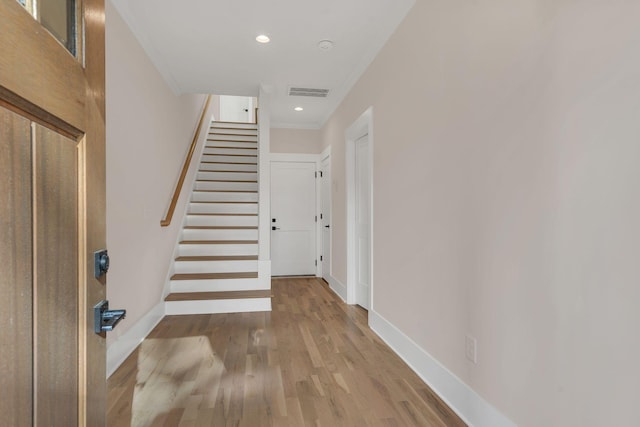 stairway with hardwood / wood-style floors and ornamental molding