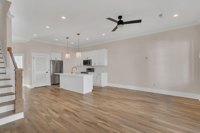 kitchen with stainless steel appliances, crown molding, pendant lighting, a kitchen island with sink, and white cabinets