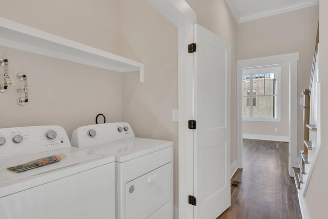 laundry room with dark hardwood / wood-style floors, washing machine and dryer, and crown molding