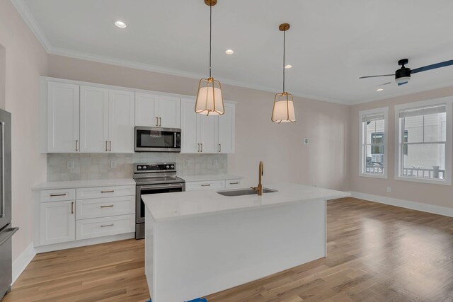 kitchen with white cabinets, appliances with stainless steel finishes, a center island with sink, and sink