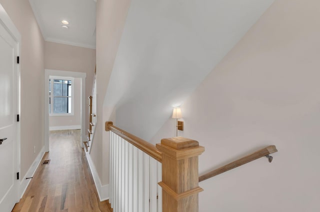 corridor with light hardwood / wood-style floors and crown molding