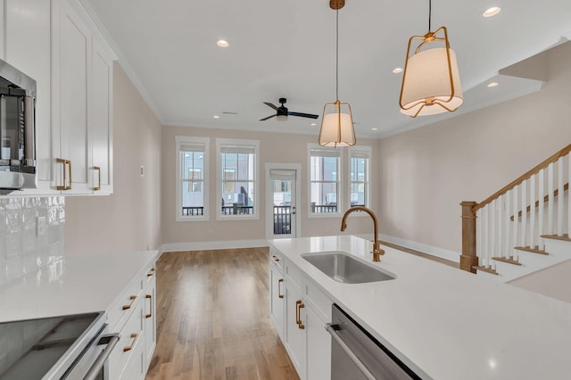 kitchen with white cabinets, ceiling fan, ornamental molding, and sink