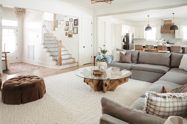 living room with light hardwood / wood-style flooring, crown molding, and a wealth of natural light