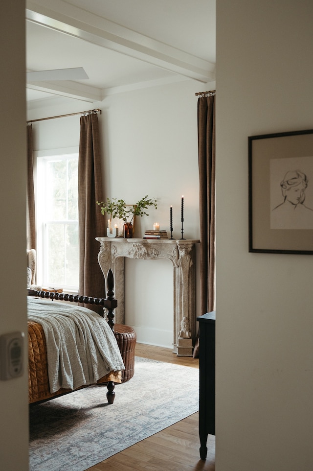 bedroom with crown molding, beam ceiling, and light wood-type flooring