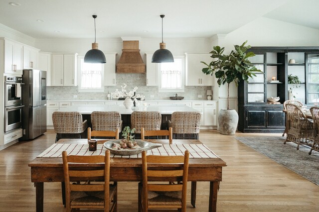 kitchen with appliances with stainless steel finishes, white cabinetry, a healthy amount of sunlight, and a kitchen island