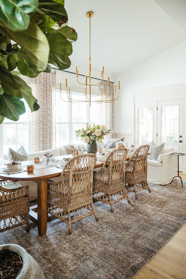 dining area with hardwood / wood-style flooring, lofted ceiling, and a chandelier