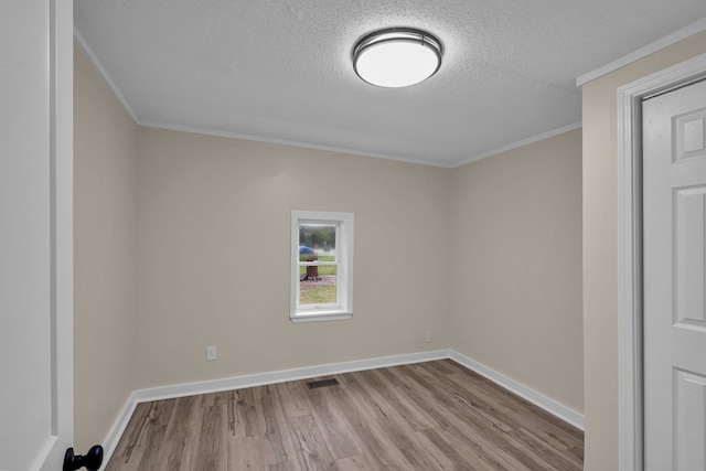 spare room featuring ornamental molding, a textured ceiling, and light hardwood / wood-style floors