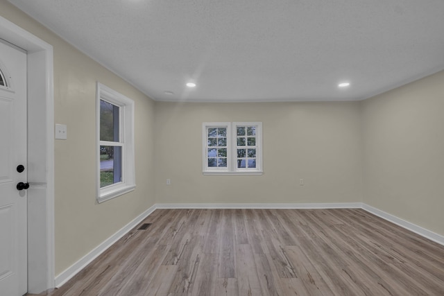 spare room with a textured ceiling and light wood-type flooring