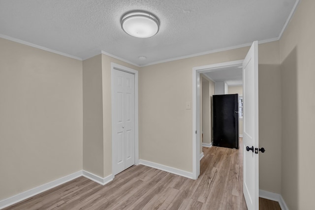 unfurnished bedroom with a closet, light hardwood / wood-style floors, crown molding, and a textured ceiling