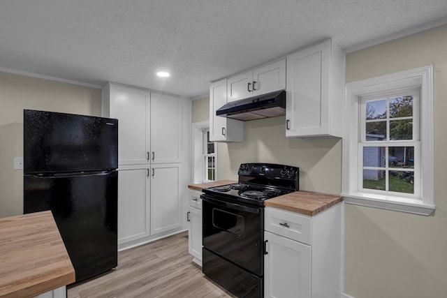 kitchen with wood counters, black appliances, light wood-type flooring, white cabinets, and a textured ceiling