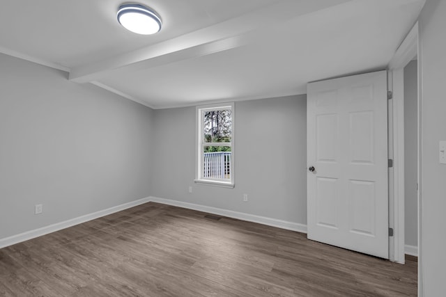 unfurnished room featuring beamed ceiling and hardwood / wood-style floors