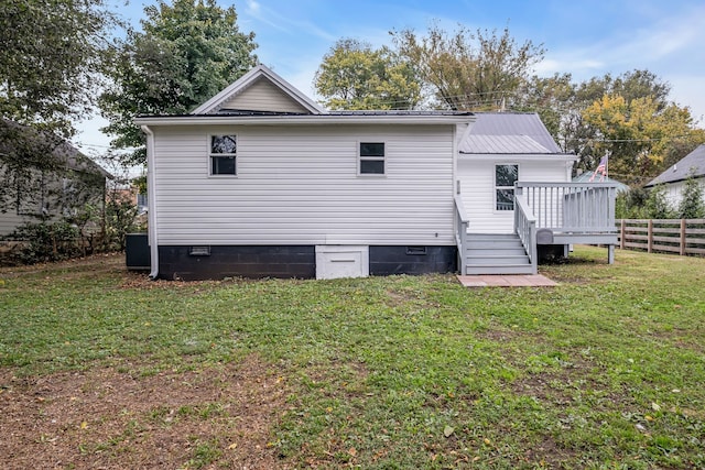 rear view of property with a deck and a lawn