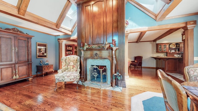 living area featuring a high end fireplace, vaulted ceiling with skylight, ornate columns, and wood-type flooring