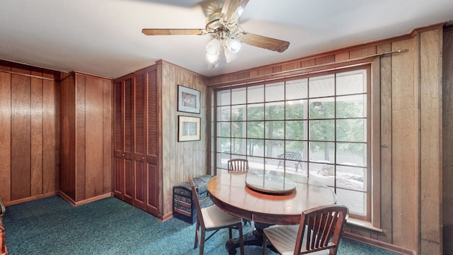 carpeted dining room featuring ceiling fan and wooden walls