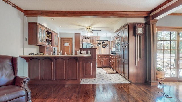 kitchen featuring kitchen peninsula, ceiling fan, a textured ceiling, light wood-type flooring, and ornamental molding