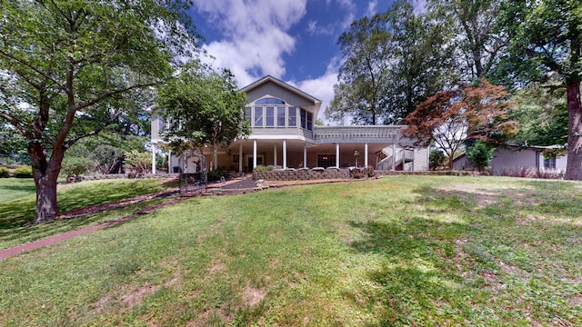 back of property with a sunroom and a lawn