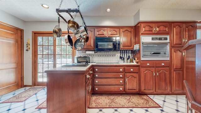 kitchen featuring a textured ceiling, tasteful backsplash, cooktop, and oven