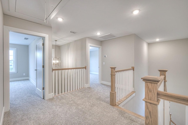 hallway featuring light carpet and an inviting chandelier