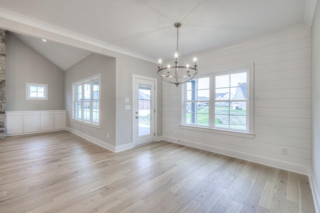 unfurnished dining area featuring vaulted ceiling, ornamental molding, a notable chandelier, and light hardwood / wood-style flooring