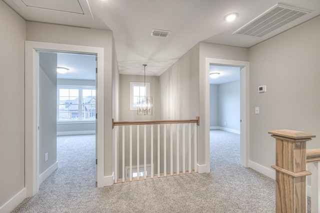 hallway featuring a chandelier and light carpet