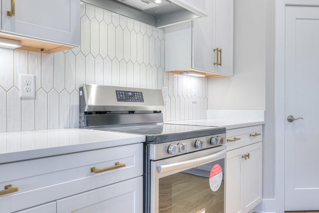 kitchen with white cabinets, wall chimney range hood, and stainless steel range with electric cooktop