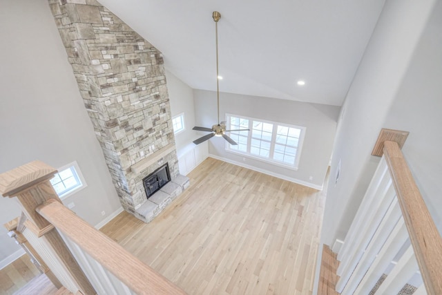 living room featuring a stone fireplace, high vaulted ceiling, and light wood-type flooring