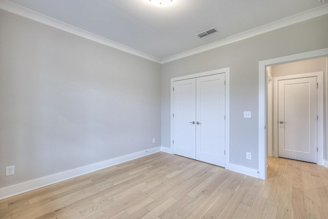 unfurnished bedroom with crown molding, light hardwood / wood-style flooring, and a closet