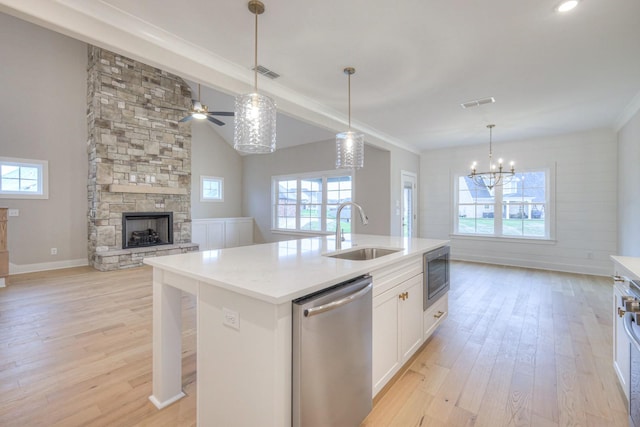 kitchen featuring a fireplace, sink, white cabinets, stainless steel appliances, and a center island with sink