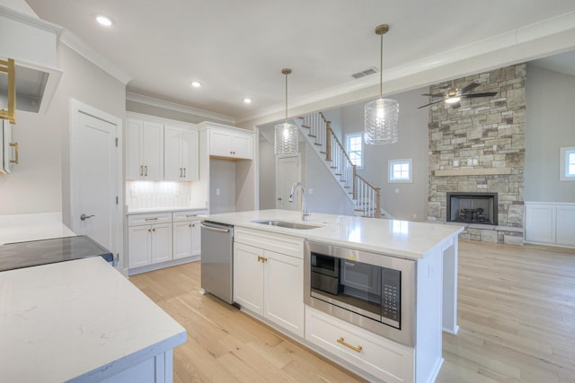 kitchen with decorative light fixtures, built in microwave, dishwasher, sink, and white cabinets