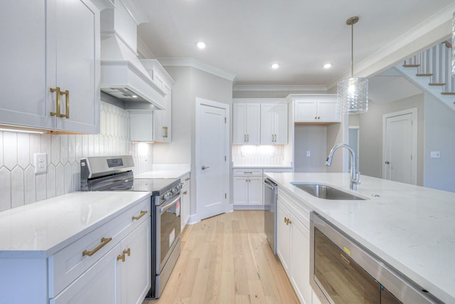 kitchen featuring sink, custom exhaust hood, white cabinetry, hanging light fixtures, and stainless steel appliances