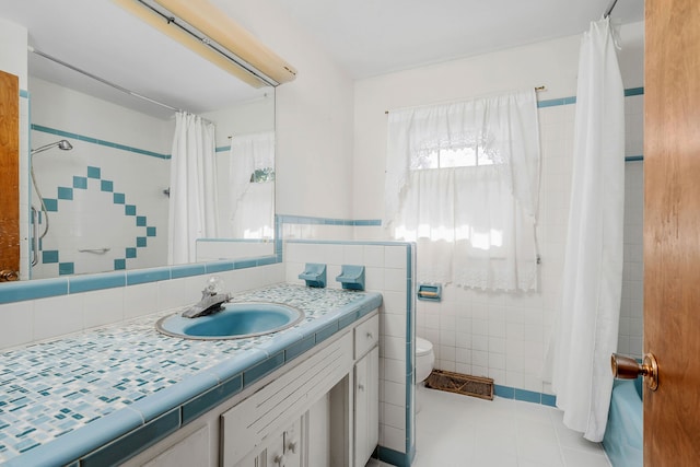 bathroom featuring tile walls, toilet, vanity, curtained shower, and tile patterned flooring