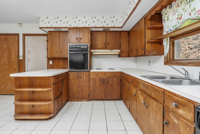 kitchen with kitchen peninsula, black oven, light tile patterned flooring, white cooktop, and sink