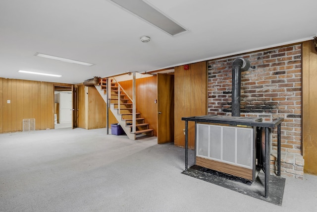 basement featuring a wood stove, wooden walls, and carpet